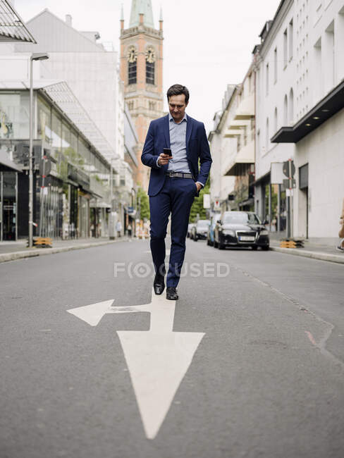 Reifer Geschäftsmann läuft mit Smartphone auf einer Stadtstraße — Stockfoto