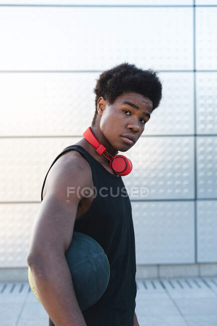 Retrato de um jovem com fones de ouvido segurando basquete — Fotografia de Stock
