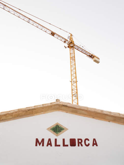 Grue industrielle se profilant contre un ciel dégagé derrière la maison à Majorque — Photo de stock