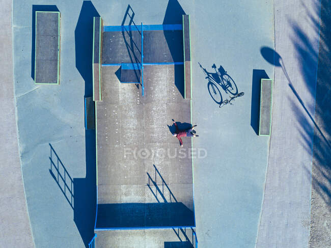 Человек лежит на бетонной рампе в скейт-парке, вид с воздуха — стоковое фото