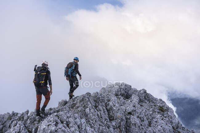 Mature males hiking on mountain against cloudy sky, Bergamasque Alps, Italy — Stock Photo