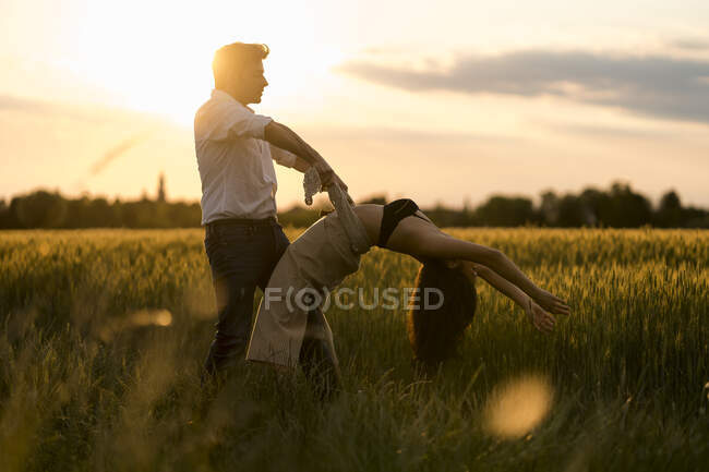 Dancing couple on field during sunset — Stock Photo