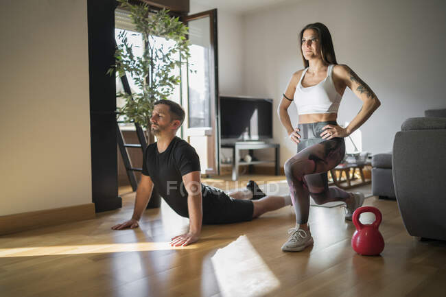 Couple exercising on floor in living room at home — Stock Photo