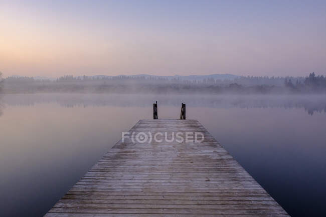 Jetty na costa do lago Kirchsee ao amanhecer nebuloso — Fotografia de Stock