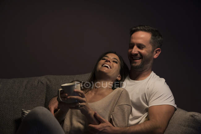 Couple heureux et aimant se détendre sur le canapé contre le mur à la maison — Photo de stock
