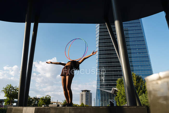 Спортивна жінка балансує пластикові обручі на грудях в сучасному місті — стокове фото
