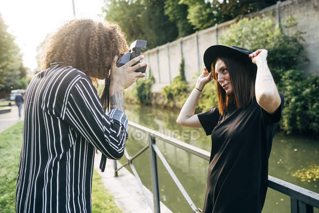 Man photographing girlfriend with camera while standing in park — Stock Photo