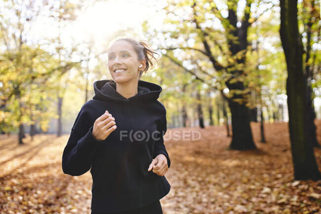 Young woman jogging in autumn forest — Stock Photo