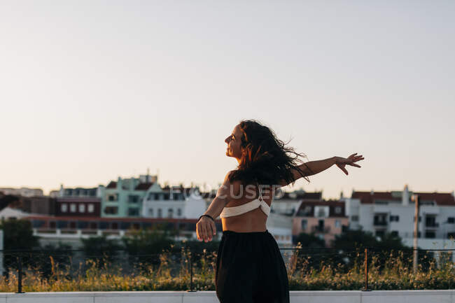 Молодая женщина с распростертыми руками, стоящая на ясном небе — стоковое фото