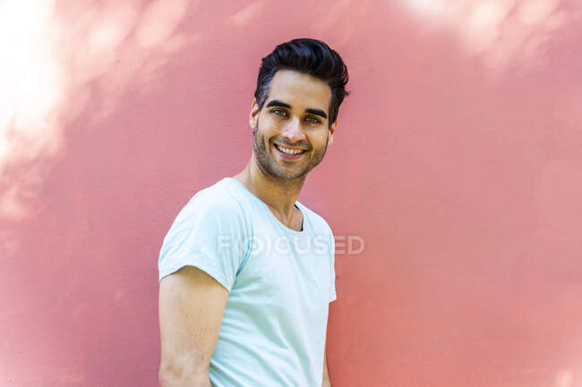 Smiling man standing against pink wall — Stock Photo