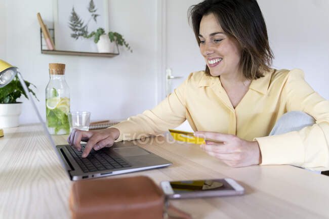 Sonriente hermosa mujer joven disfrutando de compras en línea a través de ordenador portátil en casa - foto de stock