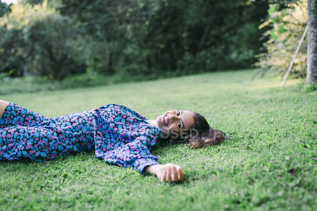 Joyeux jeune femme reposant sur des terres herbeuses dans le parc — Photo de stock
