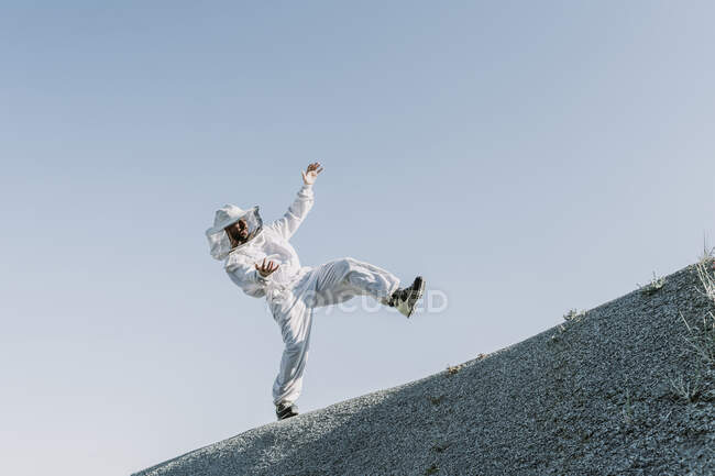Homem vestindo um vestido de apicultor caindo em uma colina — Fotografia de Stock