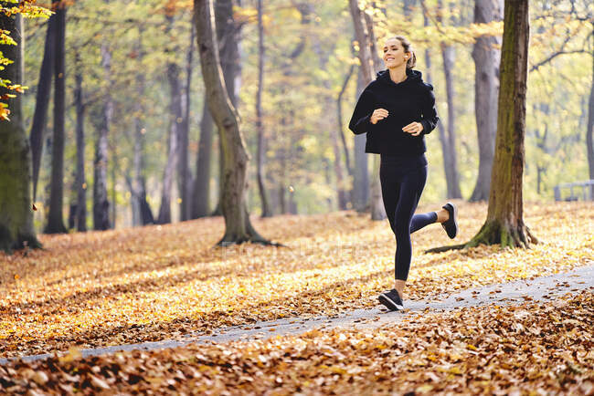Junge Frau joggt im Herbstwald — Stockfoto