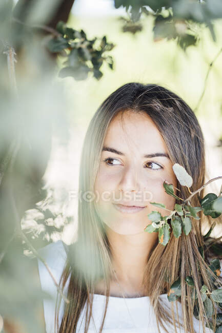 Молода жінка відвернулася, стоячи під деревом. — стокове фото