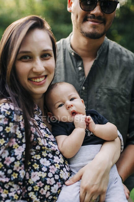 Lächelnde Frau mit Mann, der Sohn trägt — Stockfoto