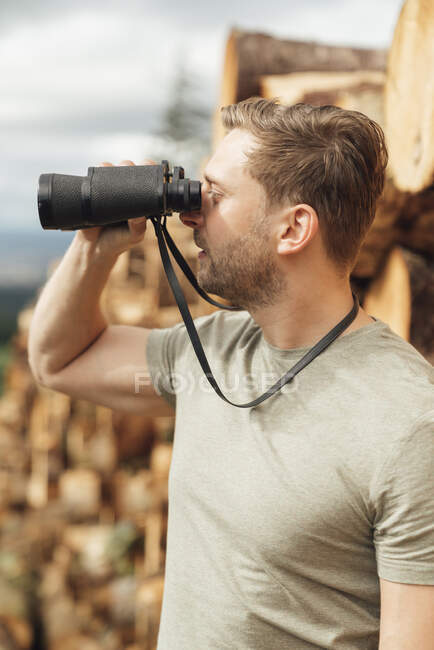 Close-up of male hiker looking through binoculars while standing in forest — Stock Photo