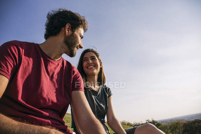Couple looking at each other while sitting against clear sky — Stock Photo