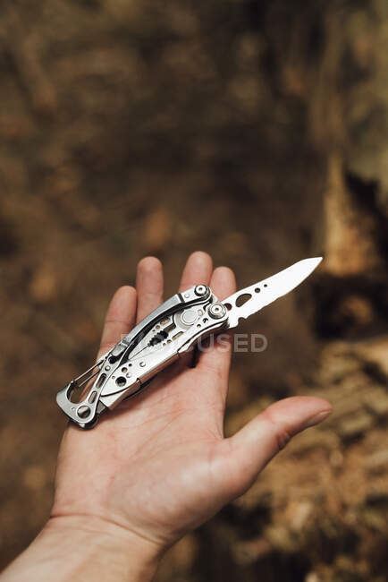 Close-up of male hiker's hand with penknife in forest — Stock Photo