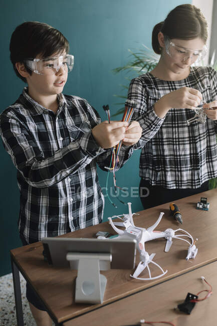 Fratelli preparare drone sul tavolo mentre in piedi a casa — Foto stock