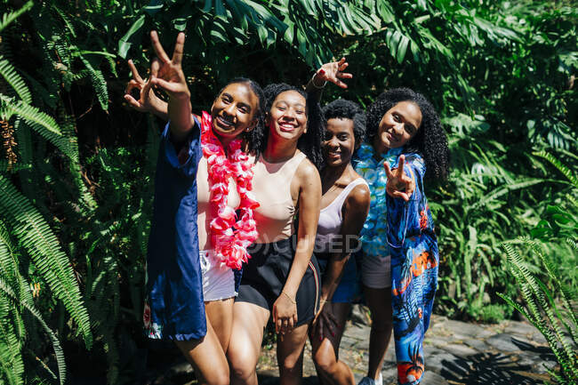 Friends showing peace sign while standing at park — Stock Photo
