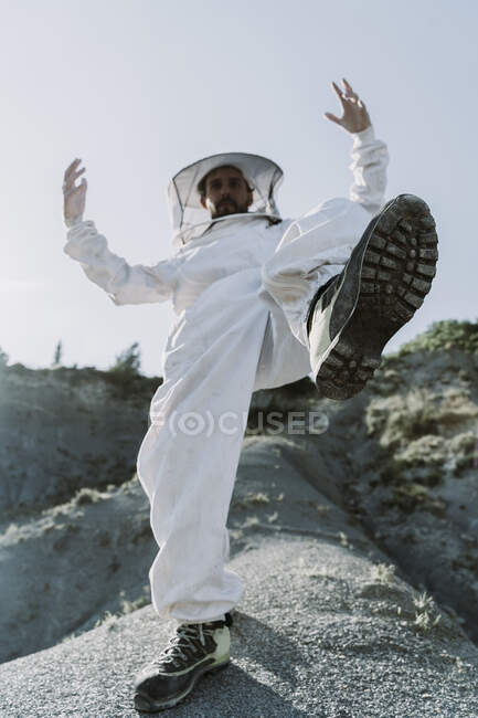 Man wearing a beekeeper dress stepping in a dry apocalyptical landscape — Stock Photo