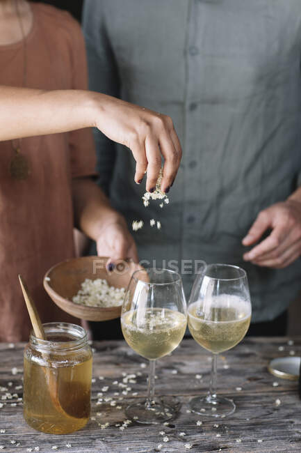 Sección media de la mujer rociando flores en cóctel en vinícola mientras está de pie por el novio - foto de stock