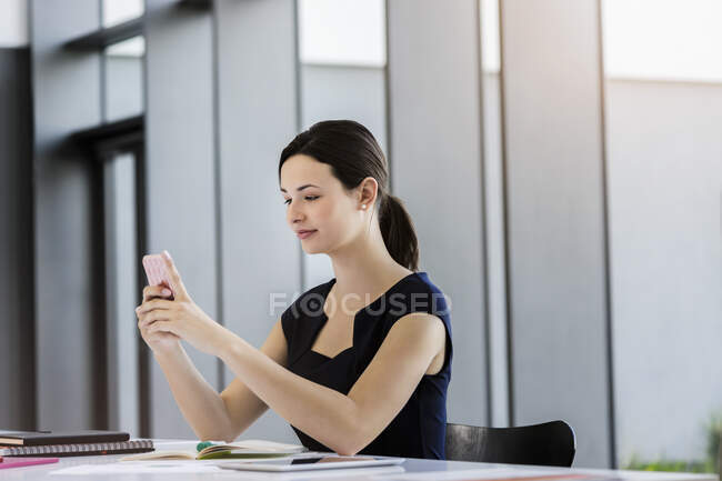 Selbstbewusste Geschäftsfrau nutzt Smartphone am Schreibtisch im Büro — Stockfoto