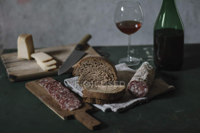 Close-up of fresh salami sausage with homemade bread and wine on table in cellar — Stock Photo