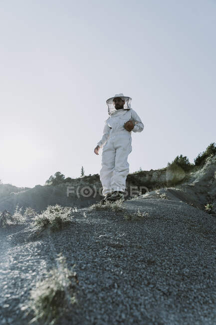 Hombre con un vestido de apicultor en un paisaje apocalíptico seco - foto de stock
