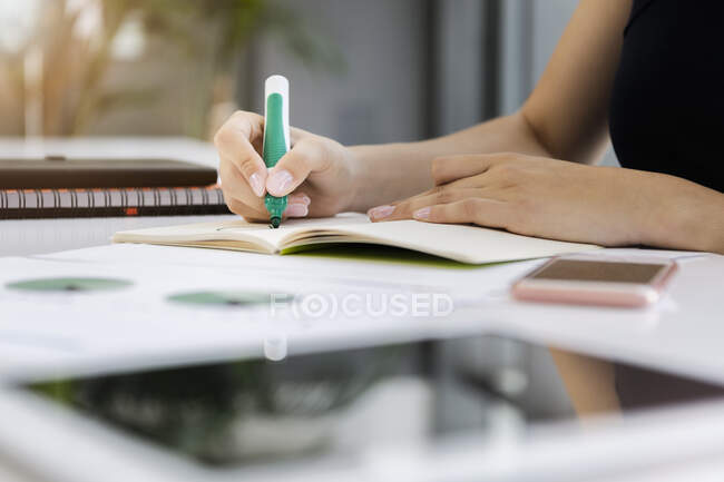 Close-up of businesswoman writing on book at desk in office — Stock Photo