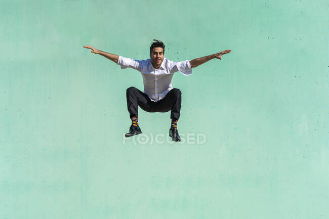 Uomo d'affari che salta davanti al muro verde — Foto stock