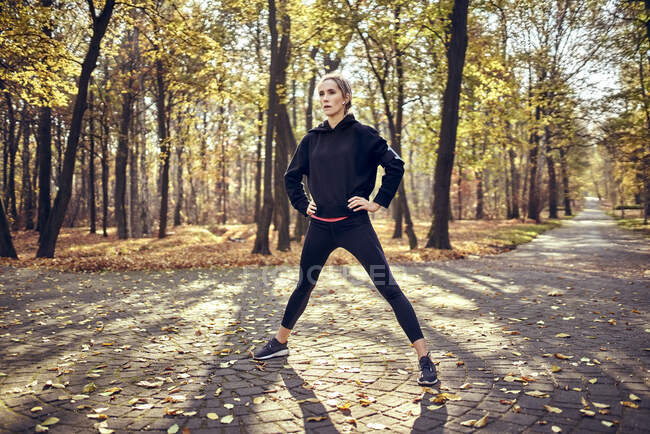Young female jogger standing with open legs in autumn forest — Stock Photo