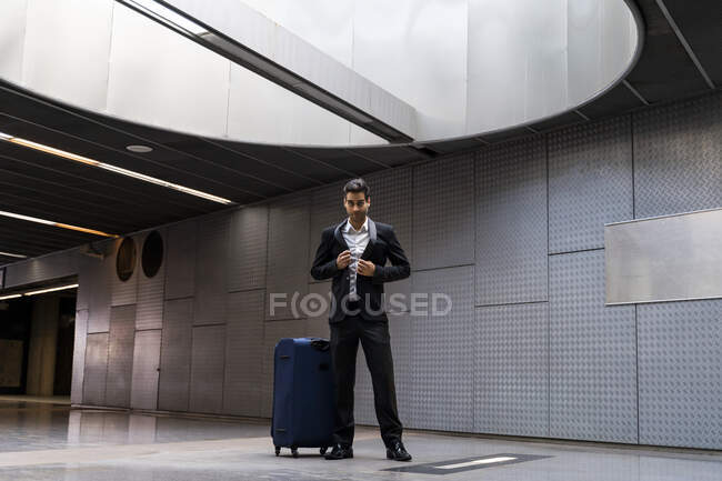 Uomo d'affari con bagaglio a ruote in piedi al piano della stazione — Foto stock