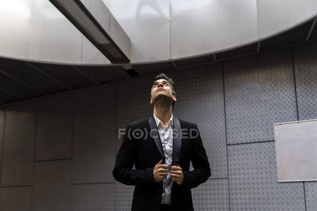 Thoughtful male professional wearing suit looking through skylight at station — Stock Photo