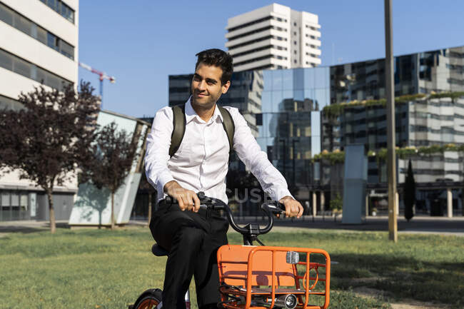 Pendolari maschi in bicicletta elettrica contro edifici in città — Foto stock