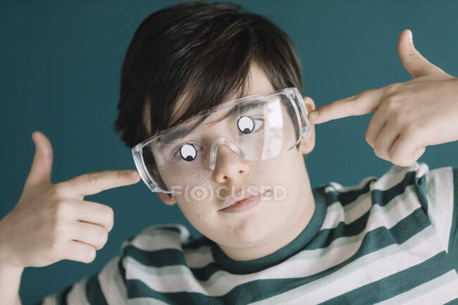Gros plan du garçon portant des lunettes avec les yeux googly contre le mur — Photo de stock