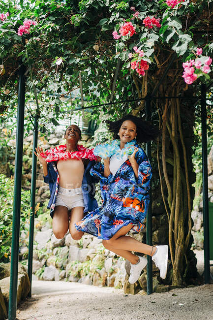 Glückliche Frauen springen im Park gegen blühenden Baum — Stockfoto