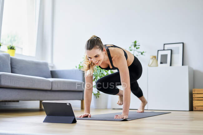 Lächelnde Frau lernt Bewegung im Internet durch digitales Tablet zu Hause — Stockfoto