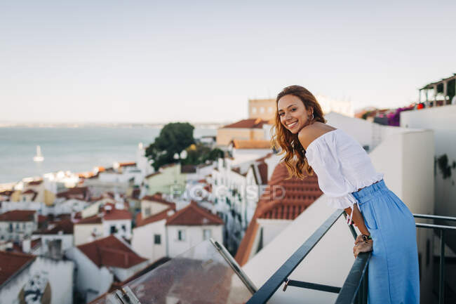 Giovane donna sorridente in piedi sul tetto ad Alfama, Lisbona, Portogallo — Foto stock