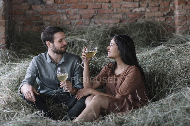 Coppia felice con cocktail seduti sul fieno nel fienile — Foto stock