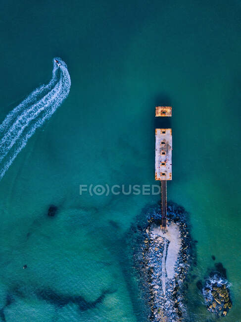 Aerial view of small pier and jet boat sailing in turquoise water — Stock Photo