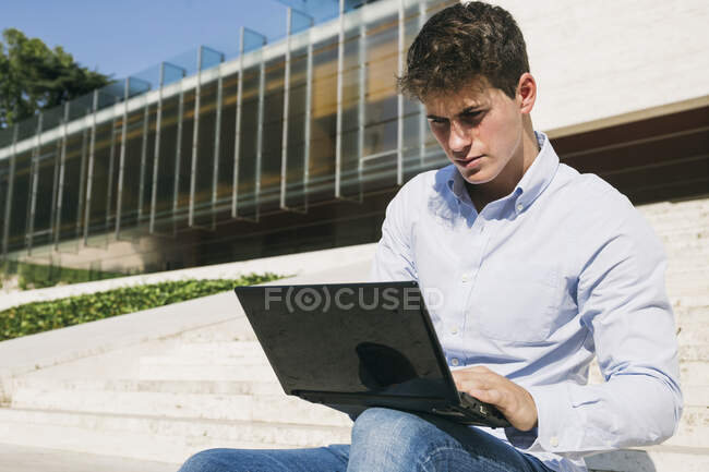 Красивый молодой человек, использующий ноутбук в солнечный день — стоковое фото