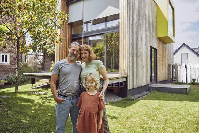 Smiling daughter standing with parents against tiny house in yard — Stock Photo