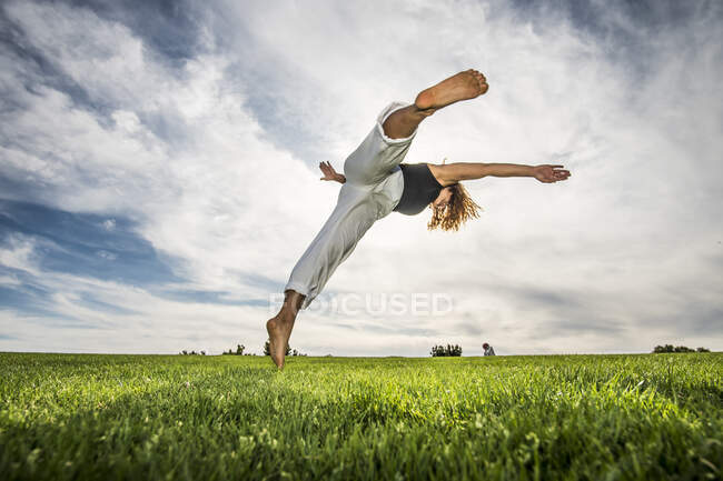 Akrobatin macht Bewegung im Park bei bewölktem Himmel — Stockfoto
