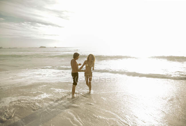Couple standing in water at beach on sunny day — Stock Photo