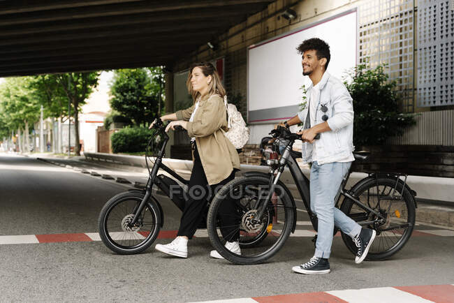 Coppia incrocio strada con biciclette elettriche in città — Foto stock