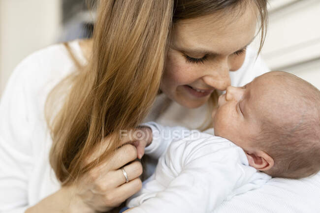 Close-up de mãe sorridente esfregando o nariz com o bebê adormecido em casa — Fotografia de Stock