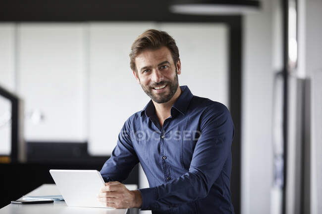 Lächelnder Geschäftsmann mit digitalem Tablet am Schreibtisch im Büro — Stockfoto