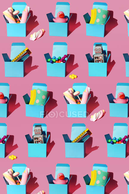 Patrón de cajas con varios regalos que incluyen armónicas, esferas de plástico, juguetes robot vintage, dulces, patos de goma y calcetines - foto de stock